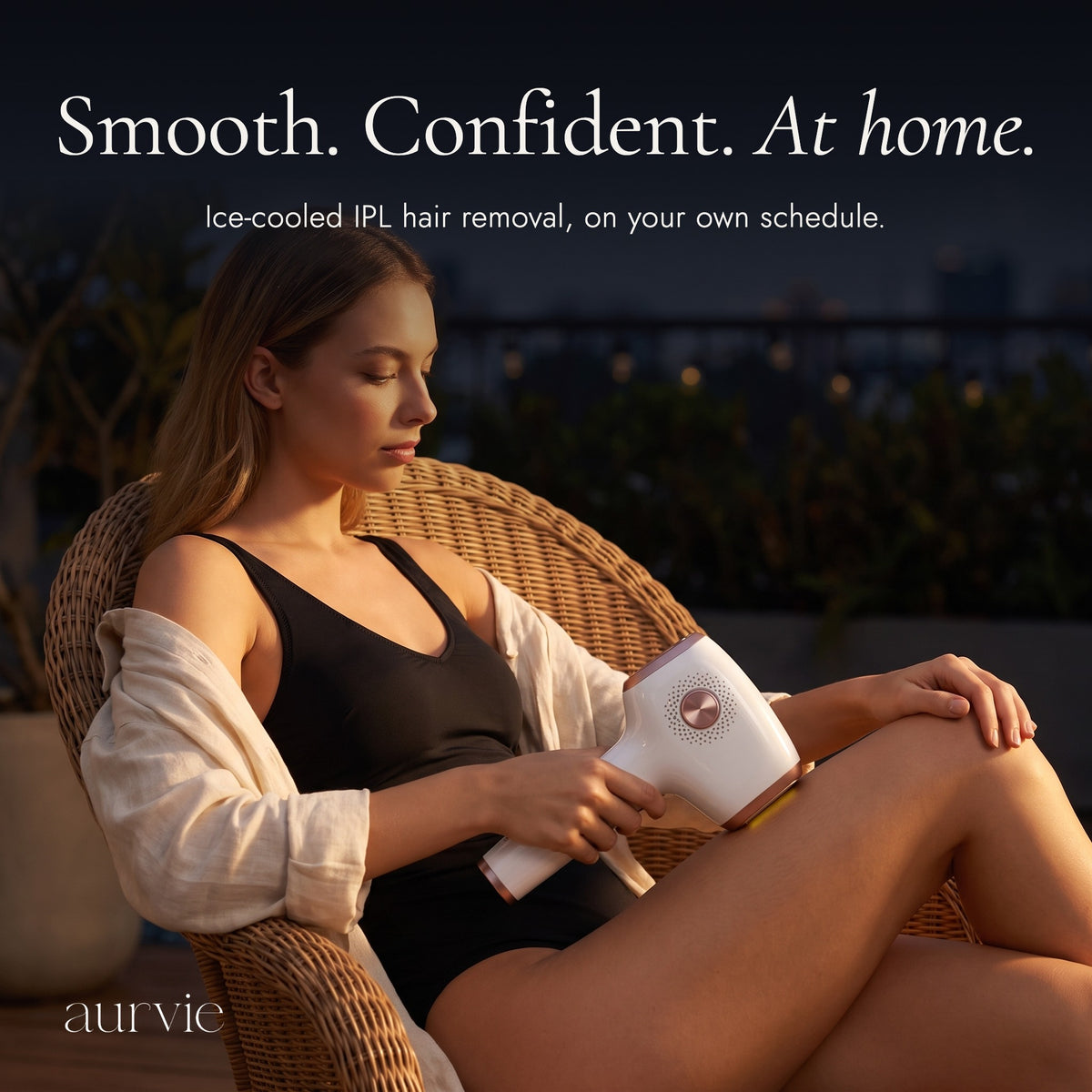 Woman on an evening terrace using the Aurvie IPL device, headline Smooth. Confident. At home. (ALT)