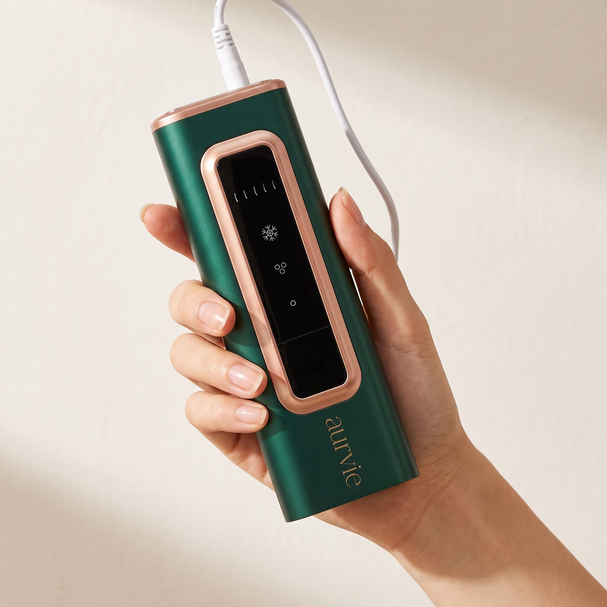 Aurvie IPL device held in one hand with its power cable (ALT)